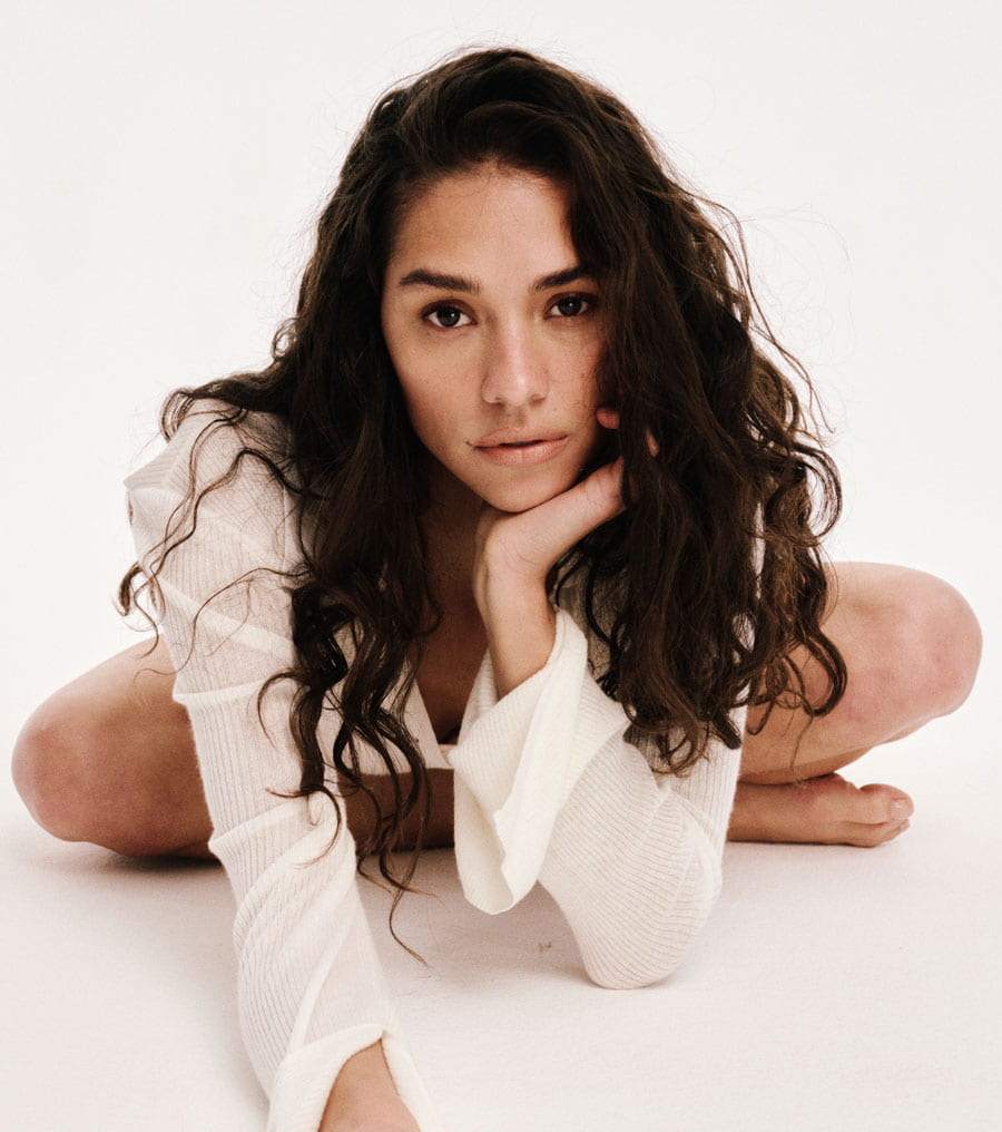 Woman in a white outfit sitting on a white background