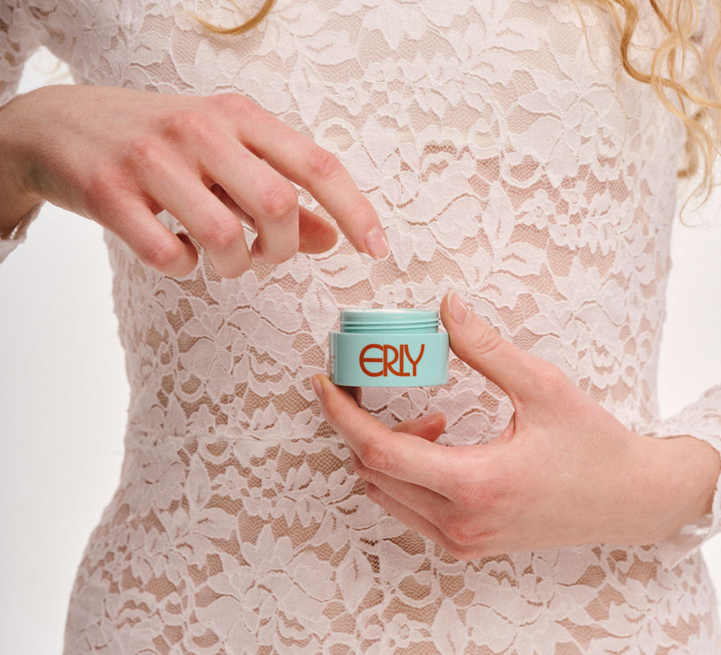 Person holding a small container labeled 'ERLY' against a lace background