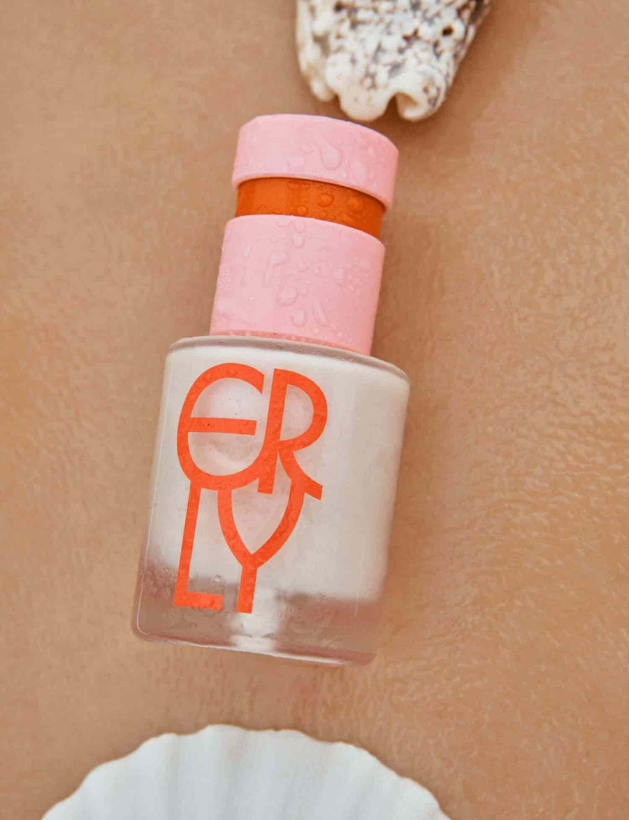 red logo on serum bottle with pink and orange topper on a body with shells