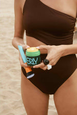 the mixer brush and erly night face moisturizer with a brown bathing suit model on the beach