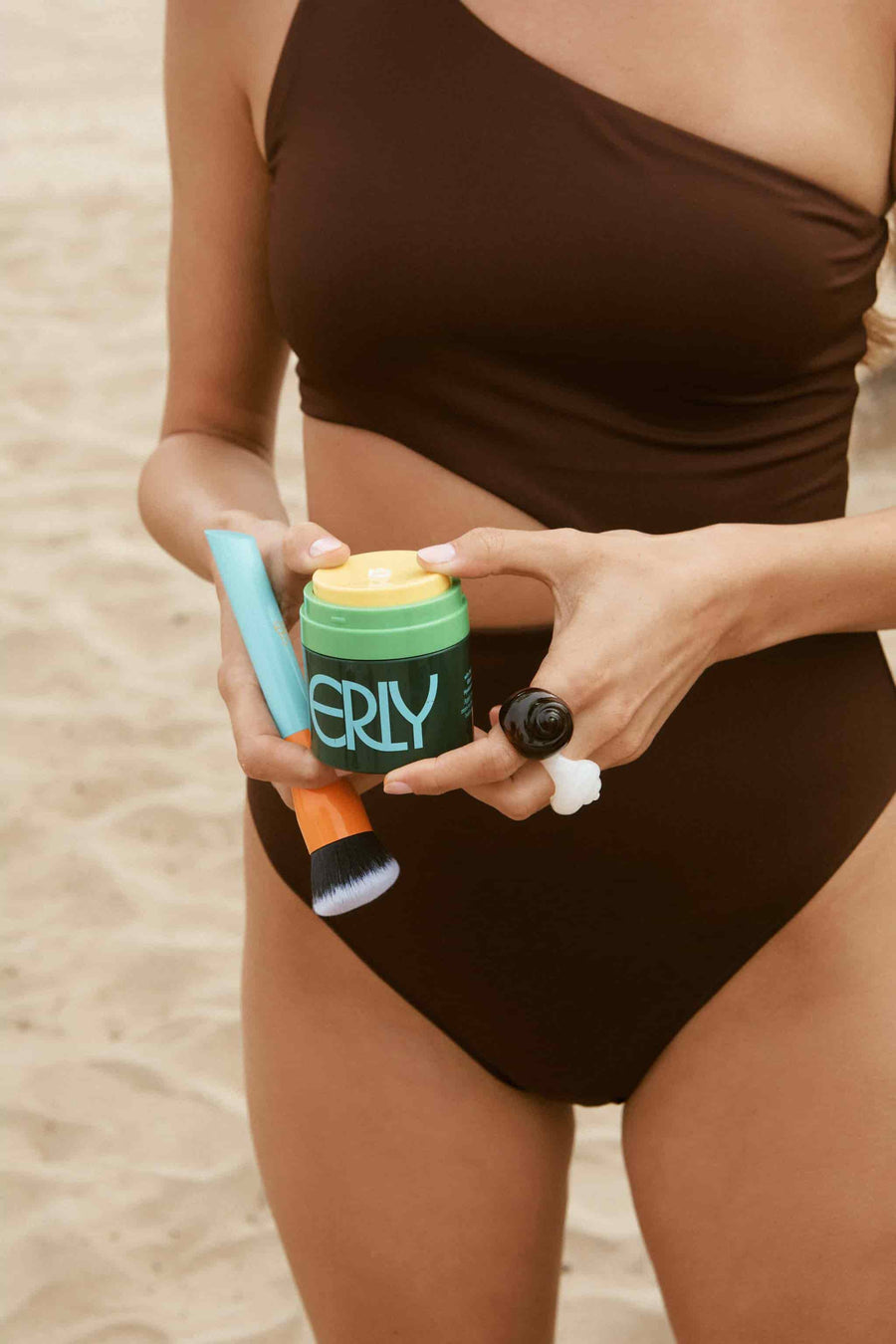 the mixer brush and erly night face moisturizer with a brown bathing suit model on the beach
