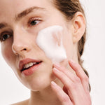 Close up of model applying ERLY Face Foam Cleanser to her cheek