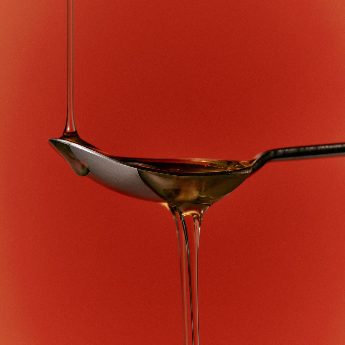 spoon on red background dripping liquid