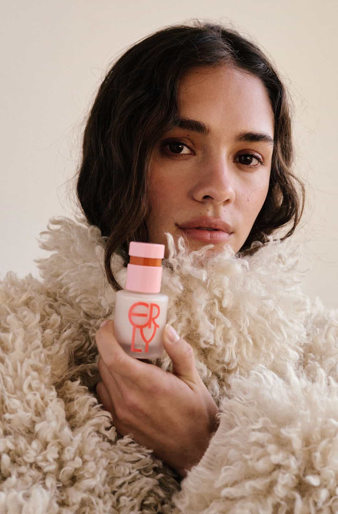 brunette girl holding product wearing a cream fur jacket