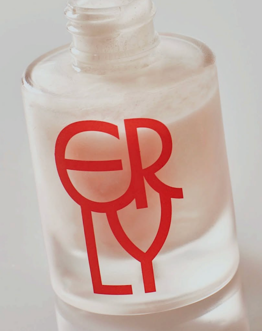 Close up of a bottle of ERLY Daily Dew Illuminating Serum with a pink logo
