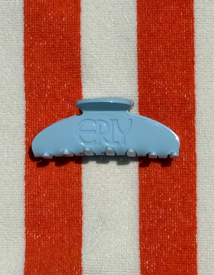 Light blue hair clip with 'ERLY' branding on a orange and white striped background