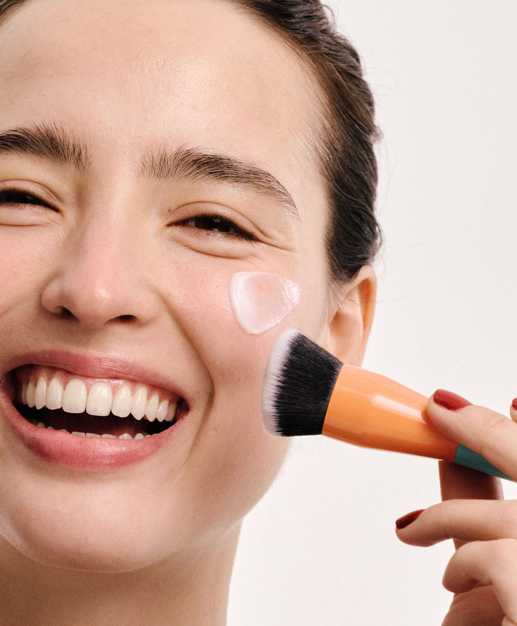 brunette putting on moisturizer with a brush 