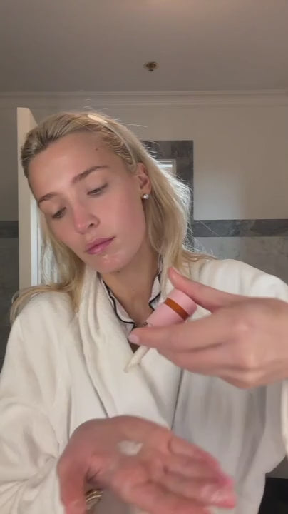 Woman in bath robe applying ERLY Daily Dew to face