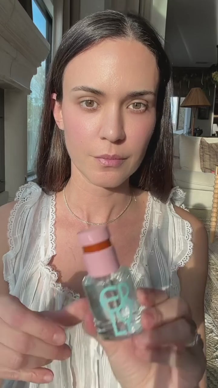 Woman applying ERLY Daily Splash to her face and neck