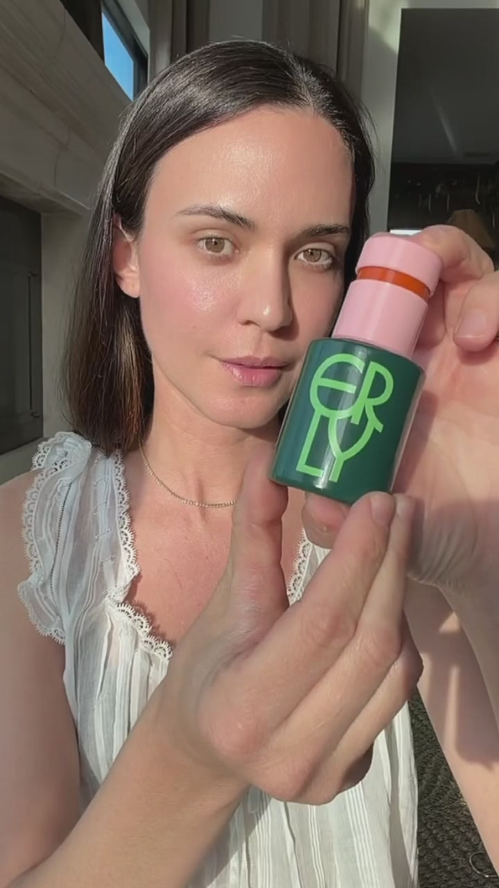 Woman applying ERLY Daily Soothe Calming Serum to her face and neck