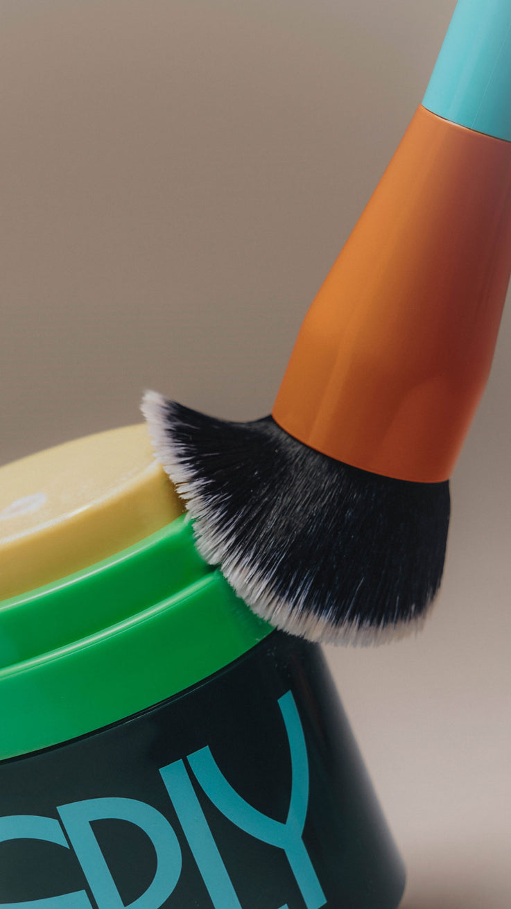 Skincare brush with orange handle and black bristles on ERLY night cream